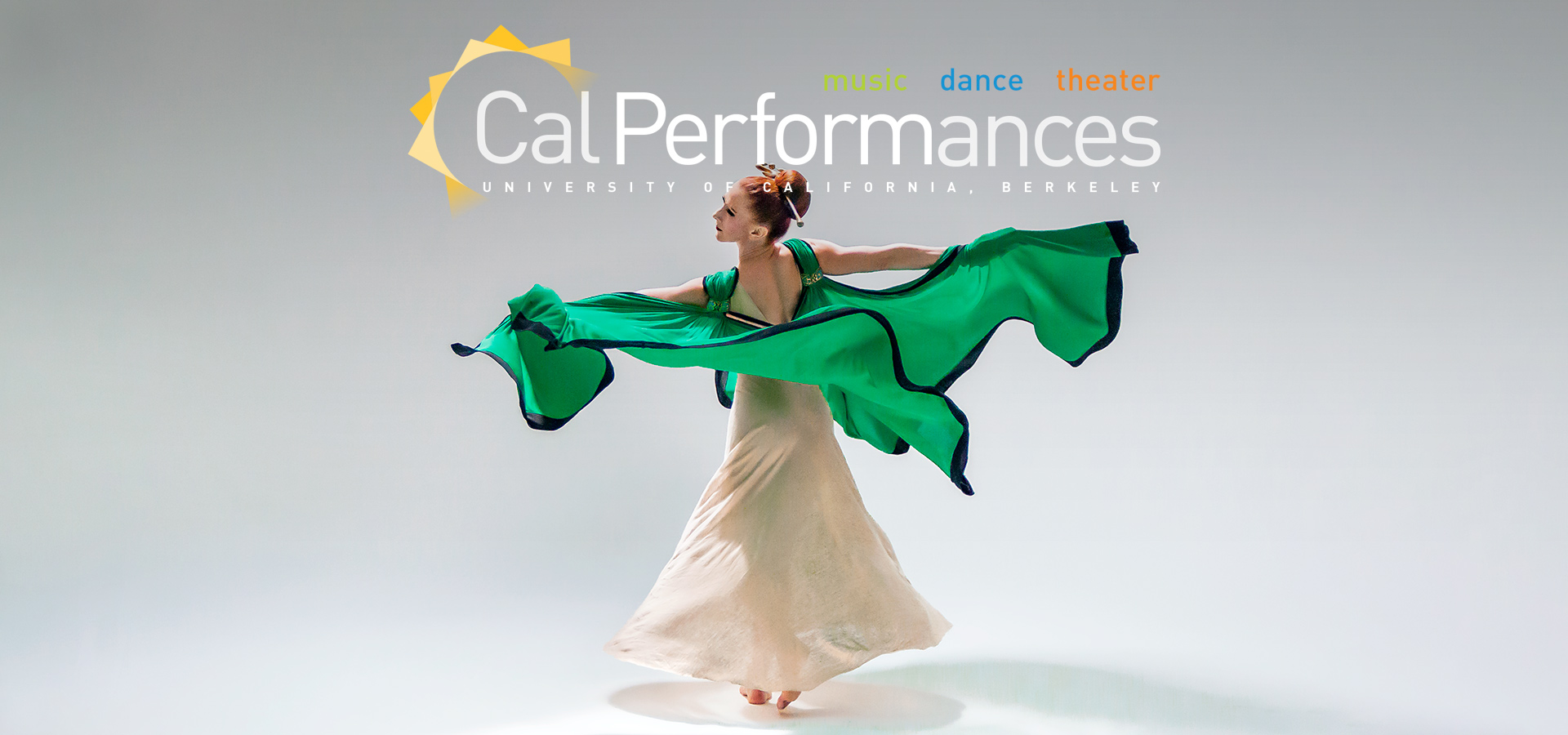 A dancer of the Martha Graham Dance Company in a flowy white dress throwing up her green cape.