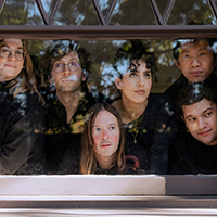 The members of yMusic group looking through a window with the reflection of trees.