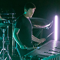 A member of Sandbox Percussion plays a vibraphone onstage holding different types of mallets in hand.