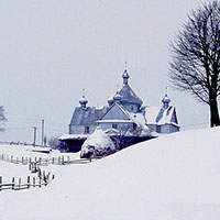 A black and white photo depicting a snowy countryside with a home and winding fence