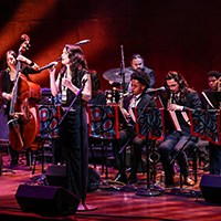The Julia Keefe Indigenous Big Band performs on a dimly lit stage in front of an audience.