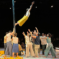 The members of Yaa Samar! Dance Theatre performing, all of them grouped together with their arms out to catch the member that jumped off the ladder.